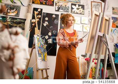 Artist wearing orange clothing standing near canvas Artist wearing orange clothing standing near canvas 54135668