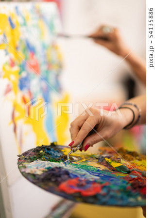 Artist with red nails wearing bracelet taking gouache Artist with red nails wearing bracelet taking gouache 54135886