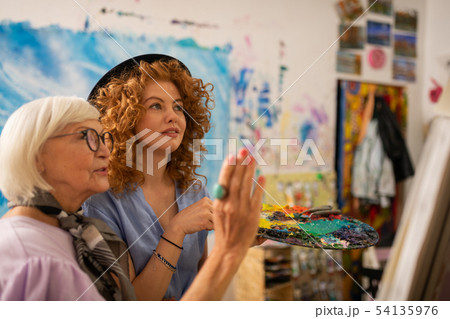 Art teacher in glasses feeling satisfied with work of her student Art teacher in glasses feeling satisfied with work of her student 54135976