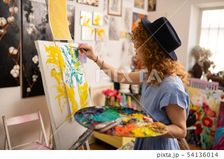 Curly red-haired artist feeling inspired while coloring picture Curly red-haired artist feeling inspired while coloring picture 54136014