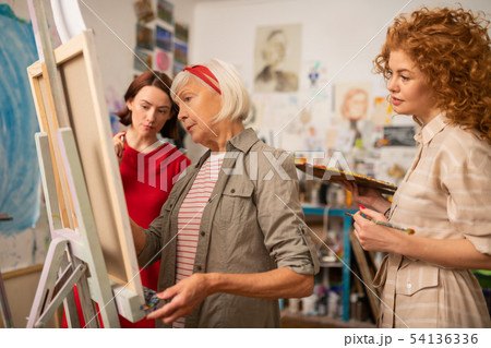 Two young women looking at famous artist painting on canvas 54136336