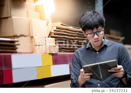 Asian man doing stocktaking on tablet in warehouse 54137231
