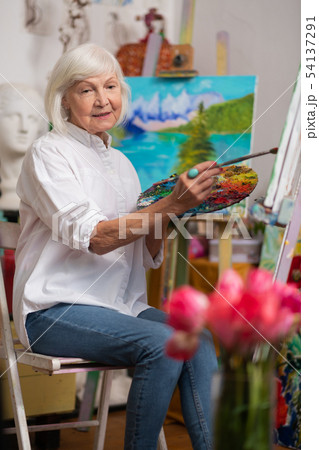 Aged woman feeling inspired while painting in the morning 54137291