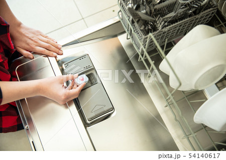 Woman puts the tablet in the dishwasher 54140617