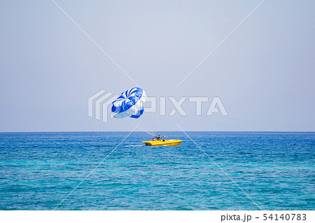 Couple of tourists flies on a blue and white parachute 54140783