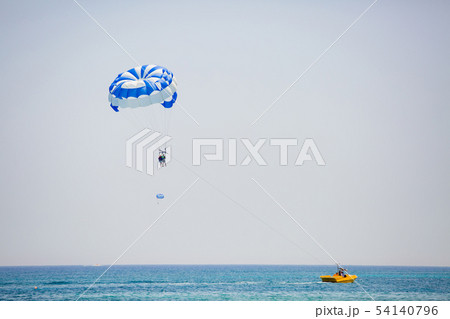 Couple of tourists flies on a blue and white parachute 54140796