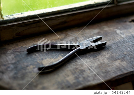 Old rusty plier on wooden shelf near window. Old rusty plier on wooden shelf near window. 54145244