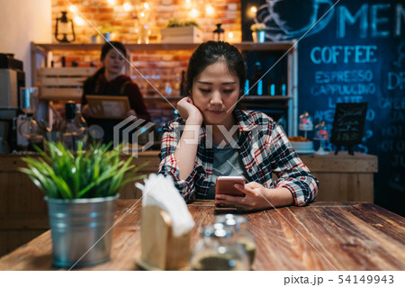 Young woman texting on mobile phone at bar Young woman texting on mobile phone at bar 54149943