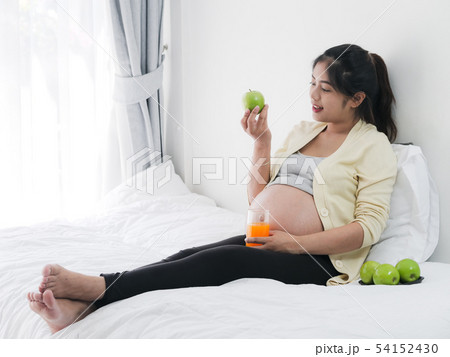 Asian pregnant woman drinking orange juice and 54152430