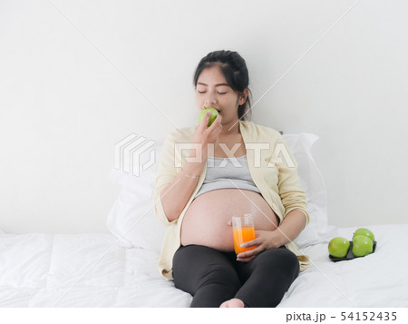 Asian pregnant woman drinking orange juice and 54152435