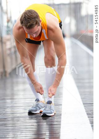 Runner man tying laces on running shoes, New York 54154985