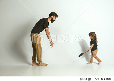 Father playing with young son against white studio background 54163466