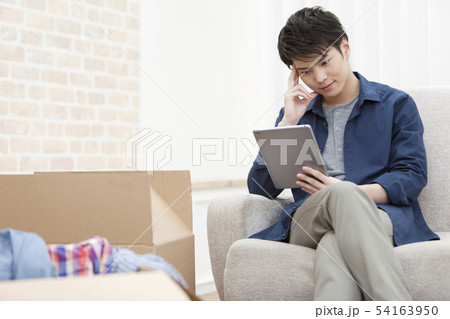 段ボールとタブレットPCを見る男性 54163950
