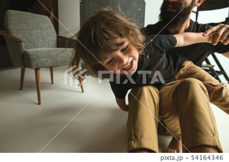 Father playing with young son in their sitting room 54164346