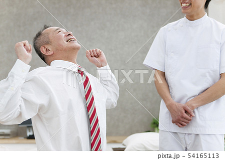 伸びをするシニア男性とマッサージ師 54165113