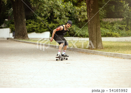 Skateboarder doing a trick at the city's street in cloudly day 54165992