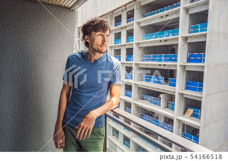 Young man on the balcony annoyed by the building works outside. Noise concept. Air pollution from Young man on the balcony annoyed by the building works outside. Noise concept. Air pollution from 54166518