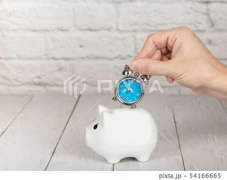 Saving time concept. Hand putting alarm clock into 54166665