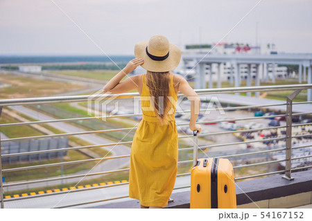 Start of her journey. Beautiful young woman ltraveler in a yellow dress and a yellow suitcase is 54167152