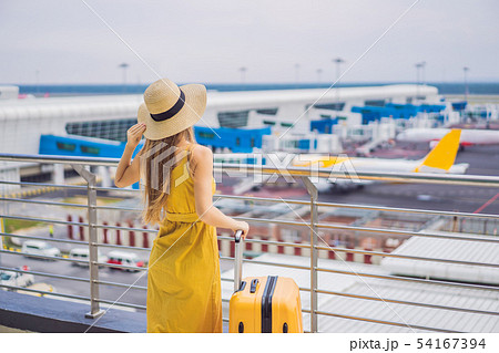 Start of her journey. Beautiful young woman ltraveler in a yellow dress and a yellow suitcase is Start of her journey. Beautiful young woman ltraveler in a yellow dress and a yellow suitcase is 54167394