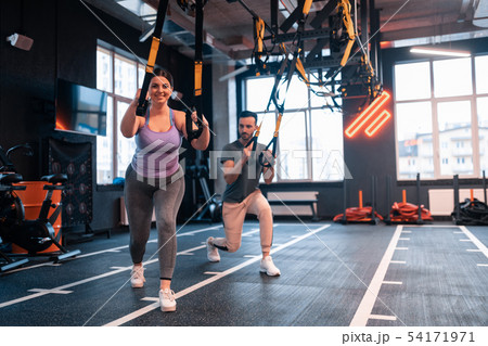 Overweight woman feeling positive while exercising with TRX 54171971