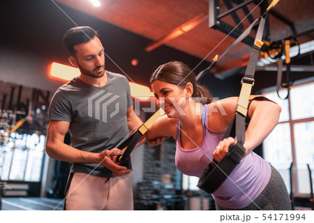 Fitness trainer assisting plump woman exercising on TRX Fitness trainer assisting plump woman exercising on TRX 54171994