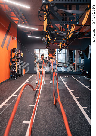 Trainer and overweight woman using TRX straps for cardio Trainer and overweight woman using TRX straps for cardio 54171998