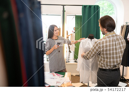 Good-looking talented fashion designer getting measurements of a dress 54172217