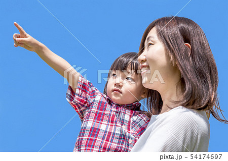 青空を背景にお母さんに抱かれ左上を指さす幼い女の子。 54174697