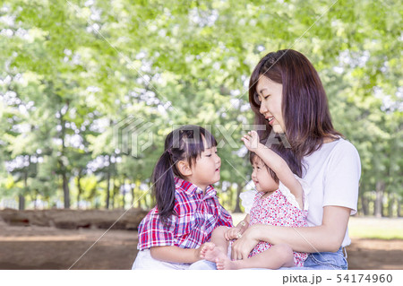 公園で緑の樹木をバックに遊ぶ母と幼い女の子3人。愛、幸せイメージ 54174960