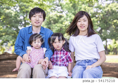 新緑の公園でカメラを見つめる家族4人。幸せ、愛情イメージ 54175210