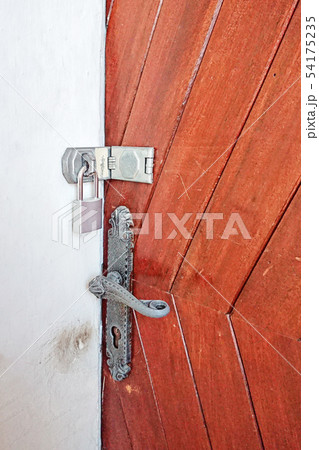 Close up view of padlock on wooden front door and door handle. Close up view of padlock on wooden front door and door handle. 54175235