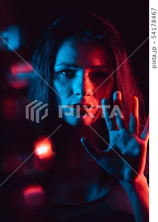 Sensual portrait of beautiful girl behind glass with raindrops with red blue lighting Sensual portrait of beautiful girl behind glass with raindrops with red blue lighting 54178467