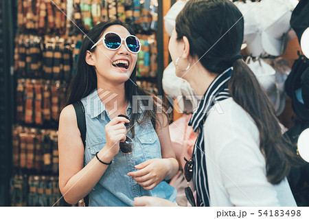 women smiling trying sunglasses with friend 54183498