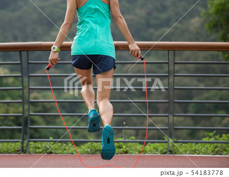 Woman athlete jumping rope on spring forest trail. Woman athlete jumping rope on spring forest trail. 54183778