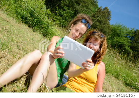 two pretty girls on the grass with a digital 54191157