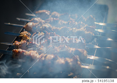Shish kebab cooking in open air in summer. barbecue skewers fried on the grill in the smoke from the 54195138