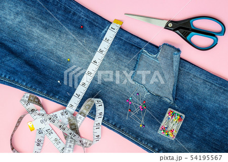 Blue jeans with a hole and talor supplies on pink Blue jeans with a hole and talor supplies on pink 54195567