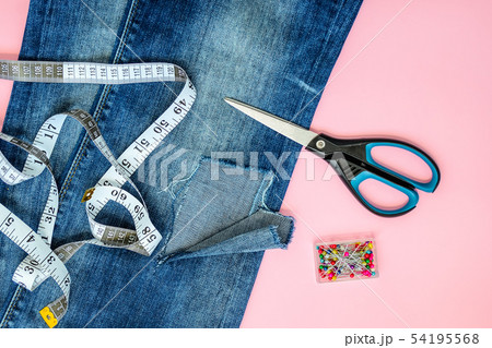 Blue jeans with a hole and talor supplies on pink Blue jeans with a hole and talor supplies on pink 54195568