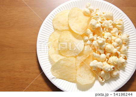 紙皿に盛り合わせられたポテトチップスとポップコーン。 54196244