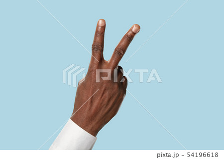 Male hand demonstrating a gesture of peace isolated on blue background 54196618