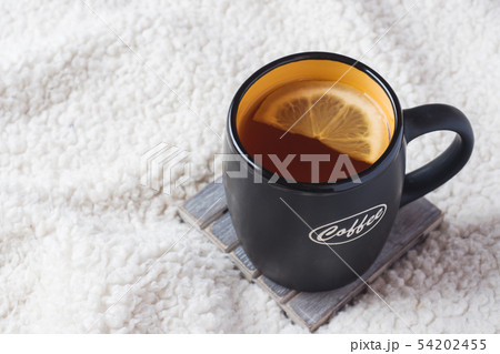 Black mug with tea and lemon on warm soft blanket Black mug with tea and lemon on warm soft blanket 54202455