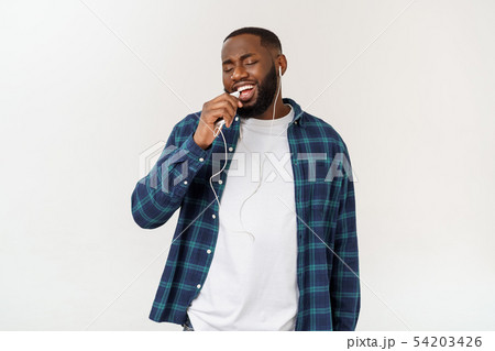 Handsome Afro American man in casual clothes is listening to music using a smart phone and smiling. 54203426