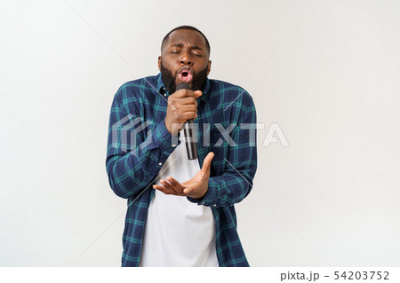 Portrait of cheerful positive chic handsome african man holding microphone singing song. Isolated on 54203752