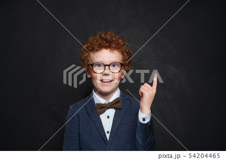 Happy redhead boy pointing up on chalkboard 54204465