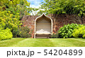 vintage wooden bench by brick wall in green garden 54204899
