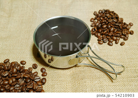 麻の布の上に置いた熱いコーヒーの入ったコッヘルとコーヒー豆 54210903