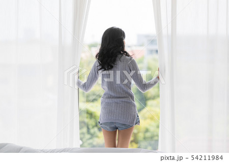Woman standing between glass door in the morning.. Woman standing between glass door in the morning.. 54211984