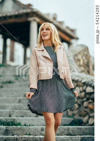 Smiling blonde girl wearing dress dancing Smiling blonde girl wearing dress dancing 54214265