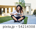 Young woman using digital tablet sitting outdoors 54214308